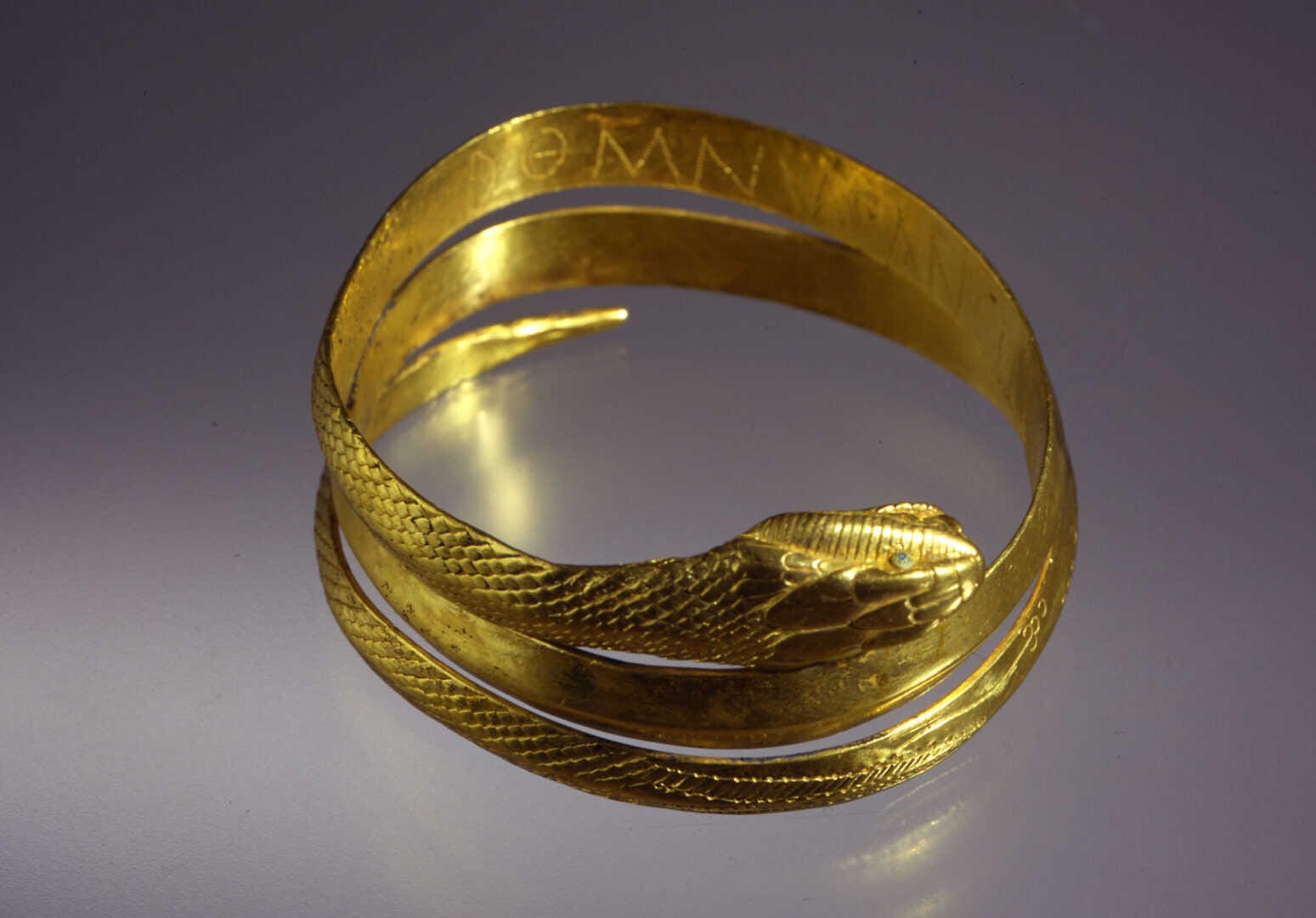 A rare Roman slave armille collar made of gold and glass, depicting a snake with engraved inscription DOM(I)NUS ANCILLAE SUAE